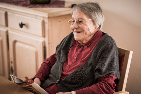 Lächelnde Seniorin sitzt am Tisch